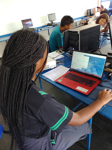 Foto dos alunos usando notebooks e computadores no curso de informática